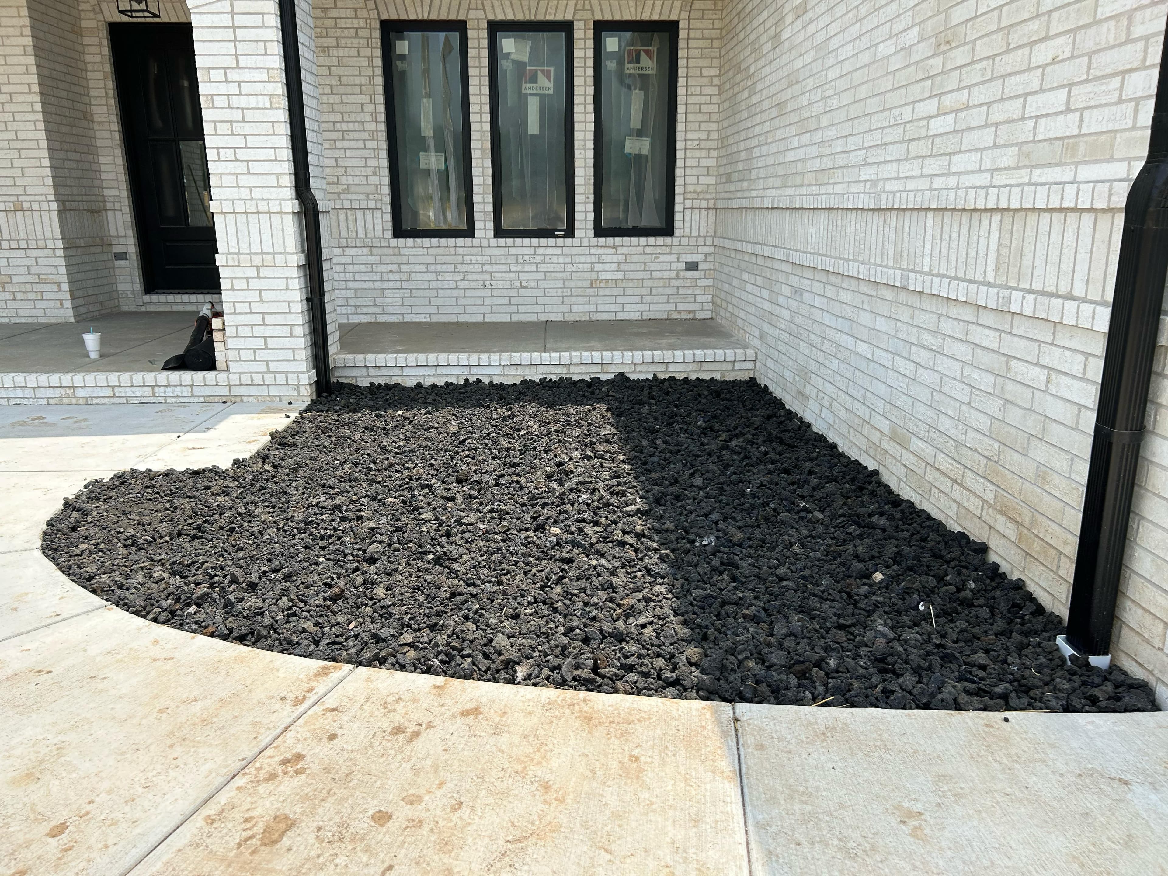 Black mulch landscaping near white brick house